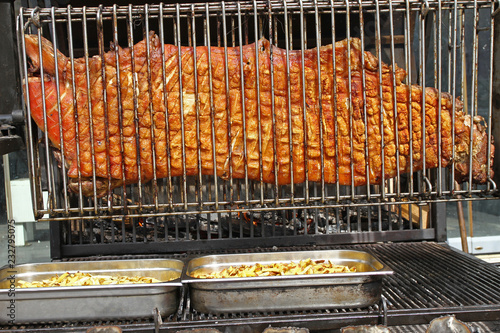 Whole pig roasted on a big grill. Kind of Cheverme, whole animal roasted on a rotating grill. A huge barbecue for a whole swine. Outdoors baking pig for Christmas holiday. Winter Happy holidays. Attra photo