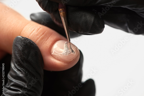 Fashionable manicure in beauty salon. Close-up of professional manicurist hands in black rubber gloves painting elegant abstract silver patterns on client woman nails using thin applicator brush. photo