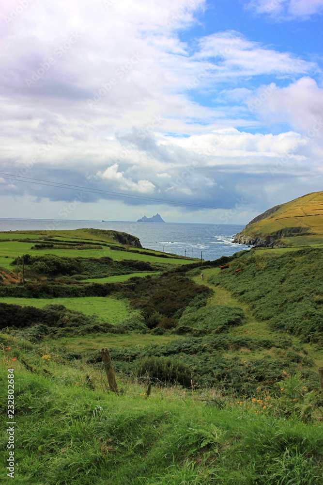 Weiter Blick bis zum Meer und Skellig Island am Horizont über irische Grashügel-Landschaft Weiter Blick bis zum Meer und Skellig Island am Horizont über irische Grashügel-Landschaft