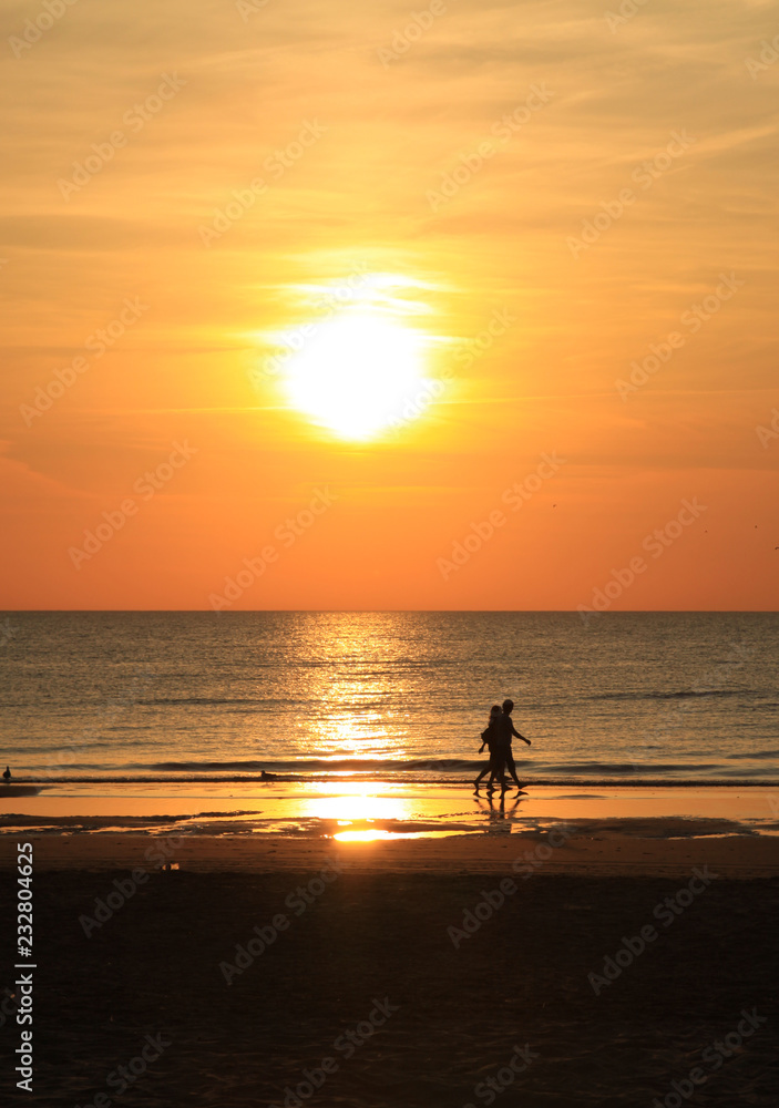 Golden sunset and people on the North Sea beach in Bloemendaal, The Netherlands.