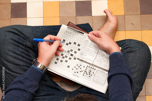 young man doing crossword puzzle in newspaper