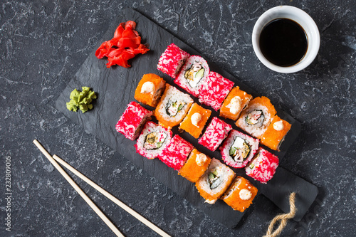 Assorted sushi rolls set served on plate on stone background.