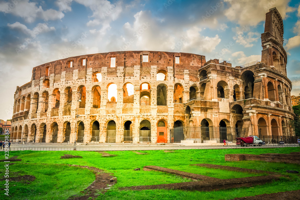 ruins of antique Colosseum with green grass lawn in sunise lights, Rome Italy, retro toned