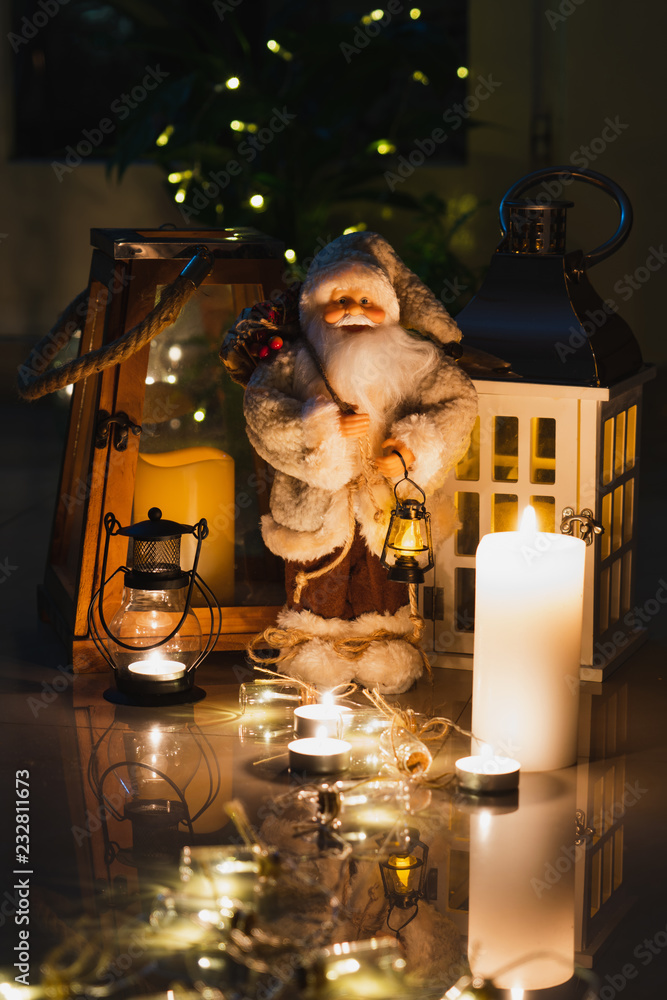Christmas decoration with a toy Santa Claus, wooden lantern, candles and garlands. Christmas decoration with a toy Santa Claus, wooden lantern, candles and garlands.