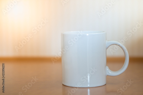 Close up of white mug cup of hot coffee on wooden table.