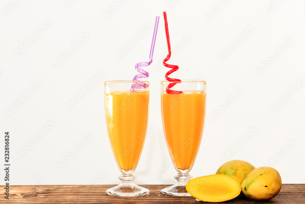 cups with mango juice on wooden countertop