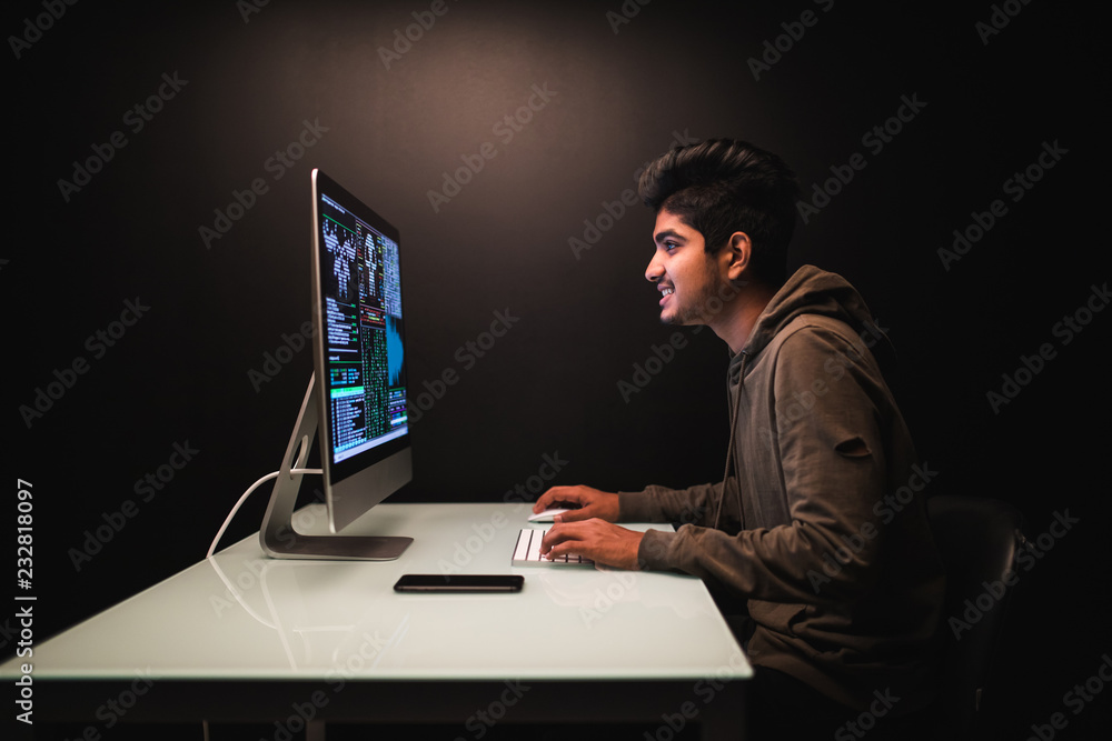 Handsome indian man hacker stole data from computer on internet, black background. Handsome indian man hacker stole data from computer on internet, black background.