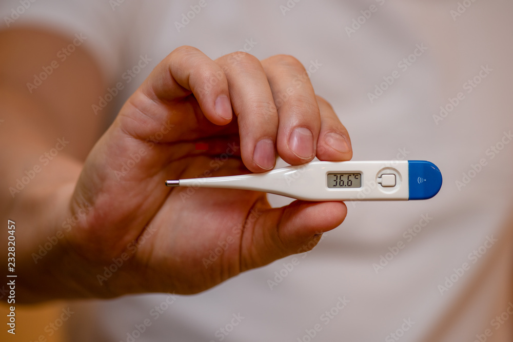 hand holding a thermometer hand holding a thermometer