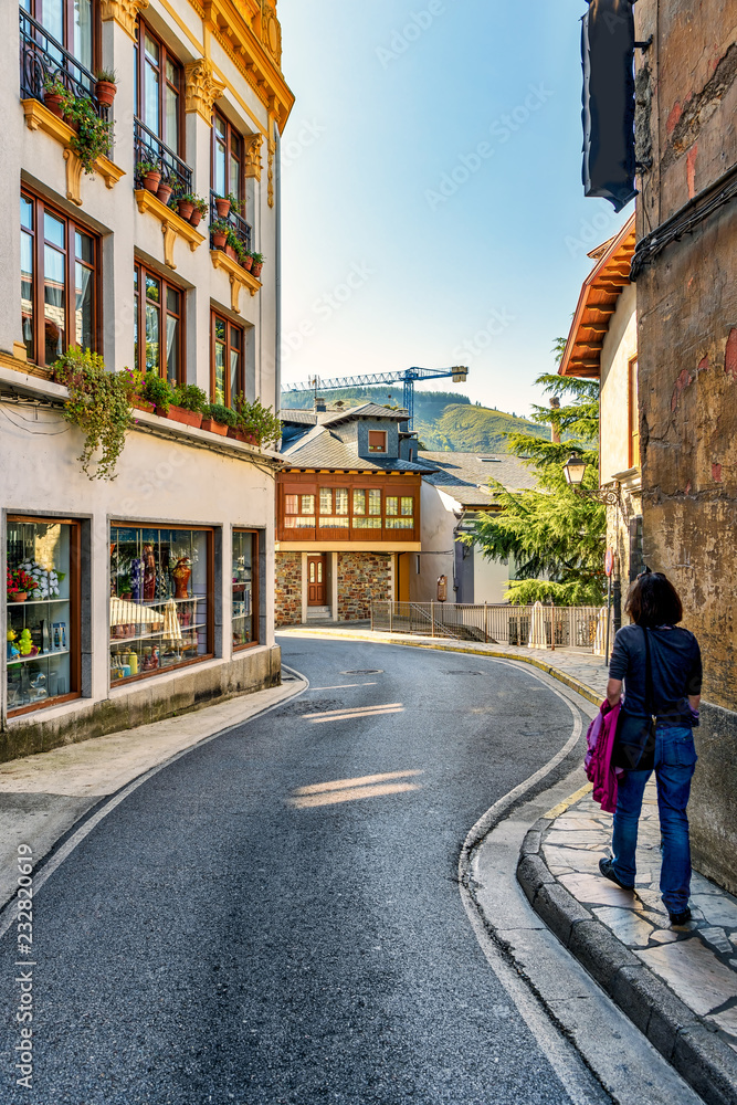 Woman walks along winding road in Villafranca del Bierzo, Spain.