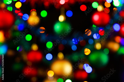 Bokeh of Christmas lights and blurred Christmas decorations with reds, greens, blues, yellows/golds and white colours. 