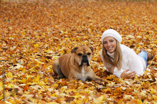 Happy woman with cute dog sitting in autumn leaves photo