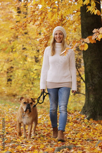 Happy middle age woman walking her dog in an autumn forest