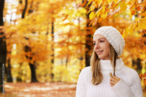 Attractive woman withscarf and cap lokking sideways in autumnal nature