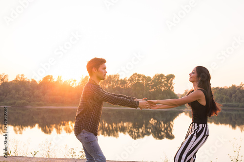 People, love and nature concept - Young beautiful couple dancing on the background of sunset