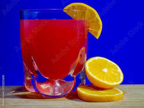 Citrus fruit cocktail quenching thirst of red with a slice of yellow lemon on a bright background.