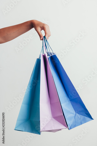 people, sale, consumerism, advertisement and black friday concept - close up of hand holding shopping bags