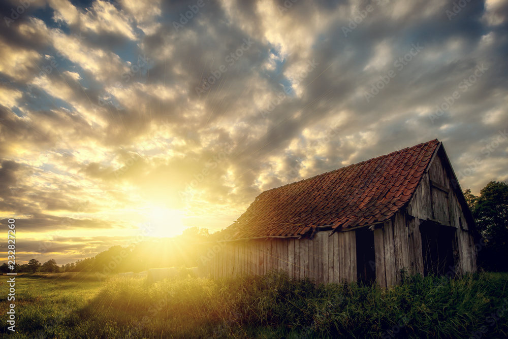 On an acre stands an old woodshed. Here during a sunset: Concept: Landscapes or Sunset
