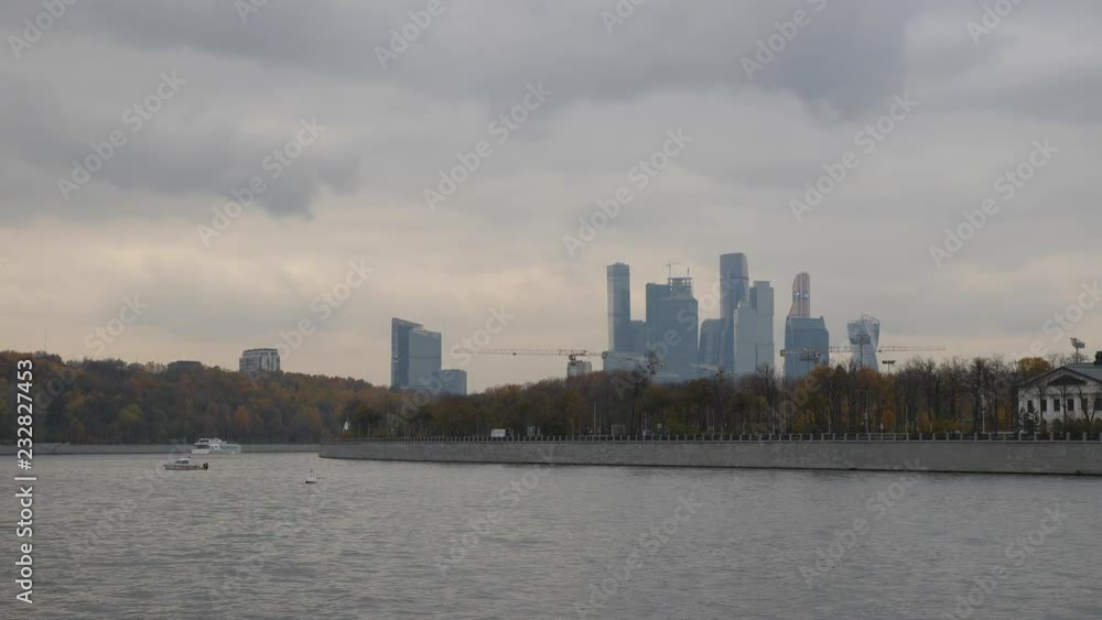 Moscow city view from the river. Late autumn in the capital's quays. Navigable walking river. Tower construction cranes towering over the autumn city park. Late autumn in the capital's quays Moscow city view from the river. Late autumn in the capital's quays. Navigable walking river. Tower construction cranes towering over the autumn city park. Late autumn in the capital's quays