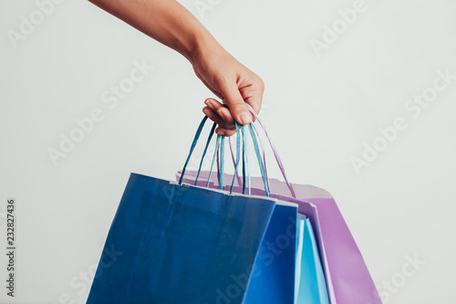 people, sale, consumerism, advertisement and black friday concept - close up of hand holding shopping bags