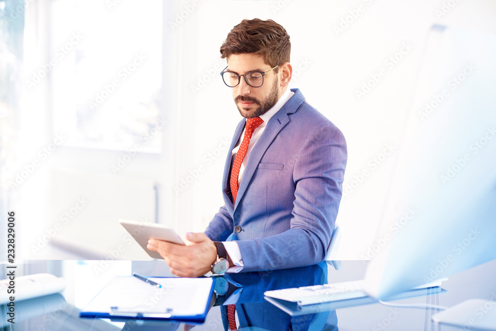 Confident busienessman with digital tablet sitting at office desk