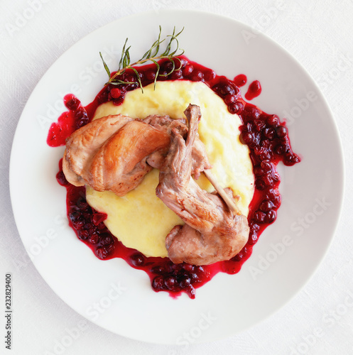 fried rabbit legs stewed with white wine, rosemary, and cranberries on potato mash with cranberry sauce decorated with fried rosemary