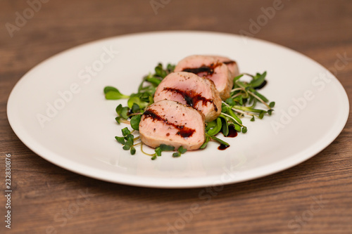 Hot Pork Tenderloin with Herbs and Spices on white plate with sauce. Selective focus. Food background