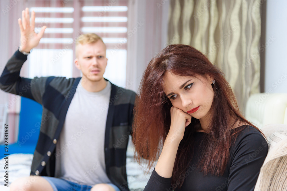 The concept of family conflict, problems, relationships of young disgruntled husband and wife in a room on the sofa. The concept of family conflict, problems, relationships of young disgruntled husband and wife in a room on the sofa.
