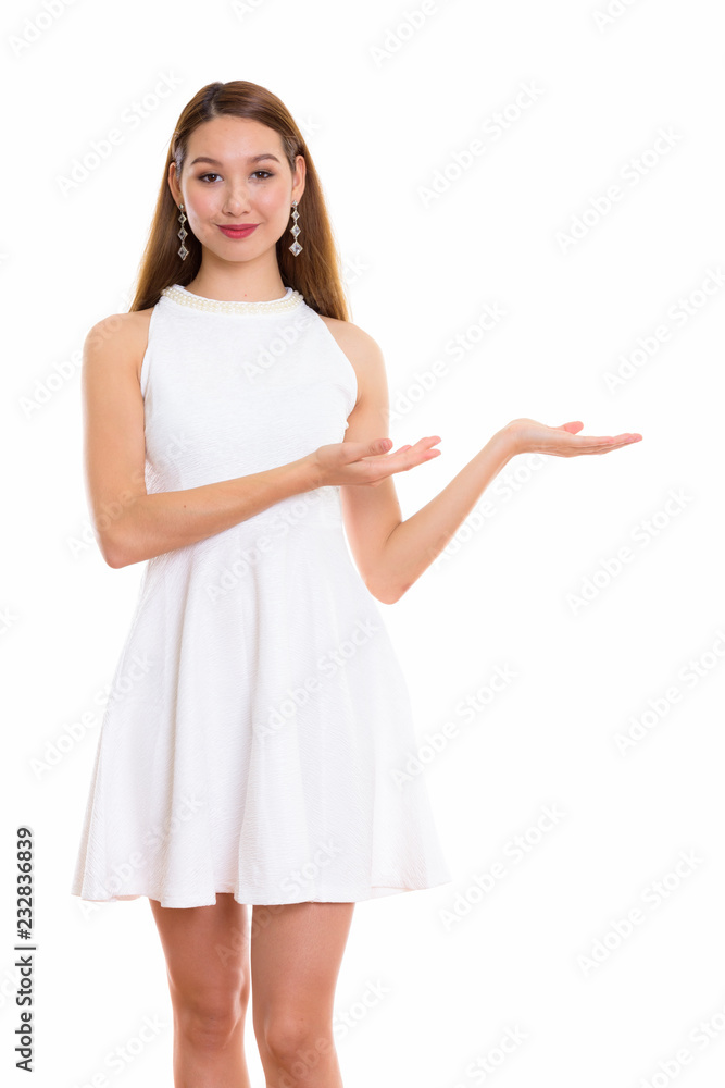 Studio shot of young beautiful Asian woman standing while showin Studio shot of young beautiful Asian woman standing while showin