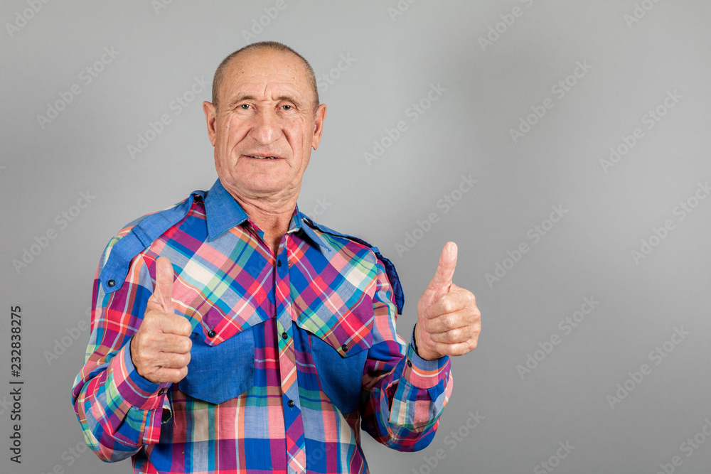 Naklejka premium Happy satisfied older older man showing thumb up on grey background.