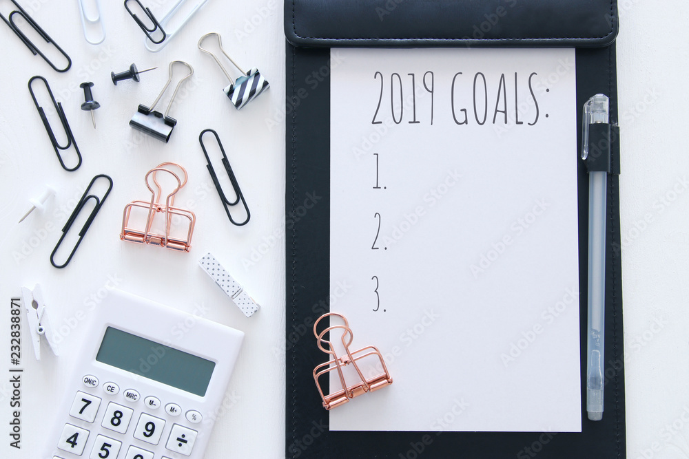 Top view 2019 goals list with notebook and calculator over wooden white desk Top view 2019 goals list with notebook and calculator over wooden white desk