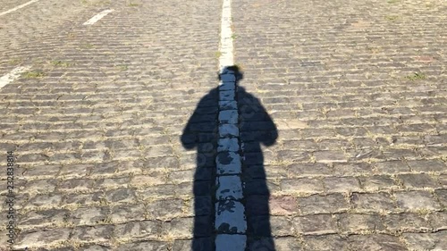 Man shadow is walking at the center of pavement road line. Slow motion 