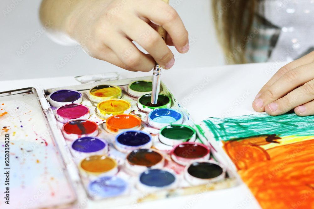child paints with watercolors and a brush child paints with watercolors and a brush