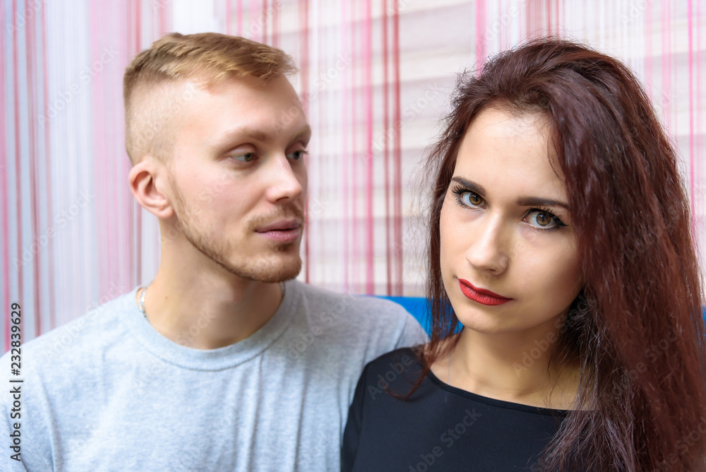 The concept of family conflict, problems, relationships of young disgruntled husband and wife in a room on the sofa. The concept of family conflict, problems, relationships of young disgruntled husband and wife in a room on the sofa.
