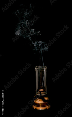 Old oil lamp with smoke on dark background