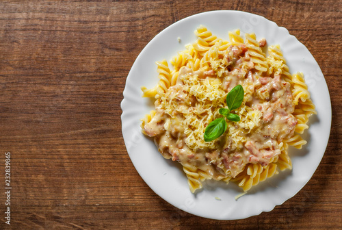 Fusilli Pasta with Carbonara Sauce and cheese in white plate on wooden table background