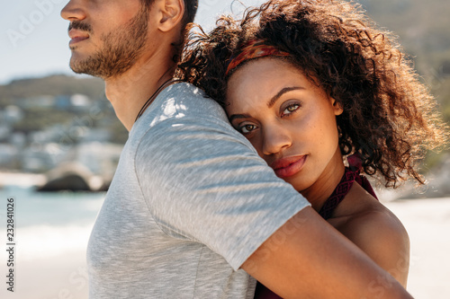 Close up of a woman standing behind a man embracing him