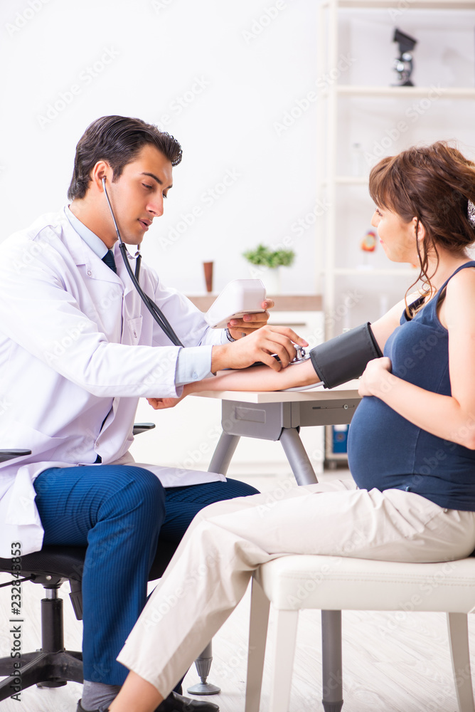 Young doctor checking pregnant woman's blood pressure Young doctor checking pregnant woman's blood pressure