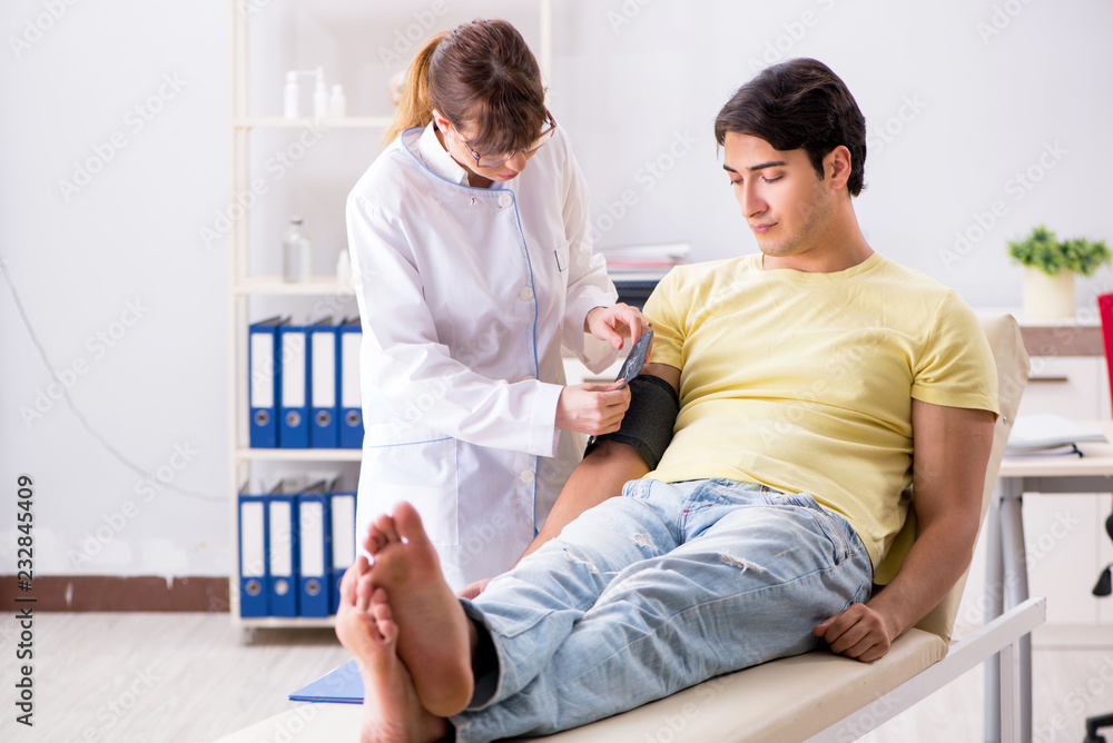 Fototapeta premium Young doctor checking patients blood pressure