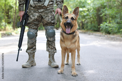 Man in military uniform with German shepherd dog, outdoors