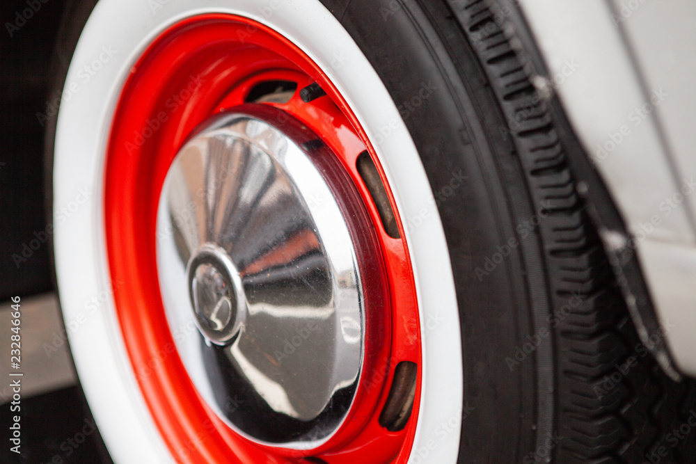 Vintage car wheel, painted red, the concept of the history of the development of cars. Close-up.