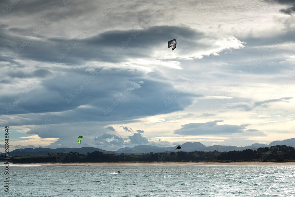 kite surfers practicando en el mar , uno de ellos vuela muy alto debido al gran viento