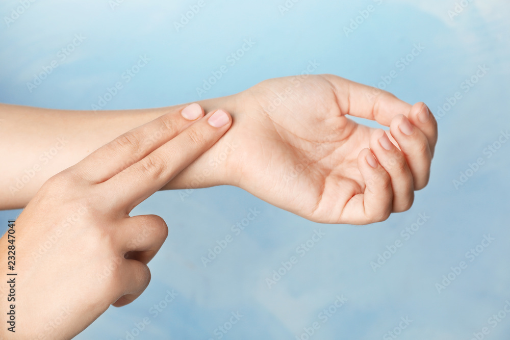 Woman checking pulse on wrist against color background, closeup Woman checking pulse on wrist against color background, closeup