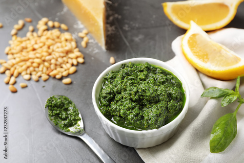 Bowl and spoon with basil pesto sauce on table