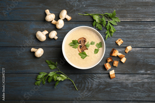Flat lay composition with bowl of fresh homemade mushroom soup on wooden background