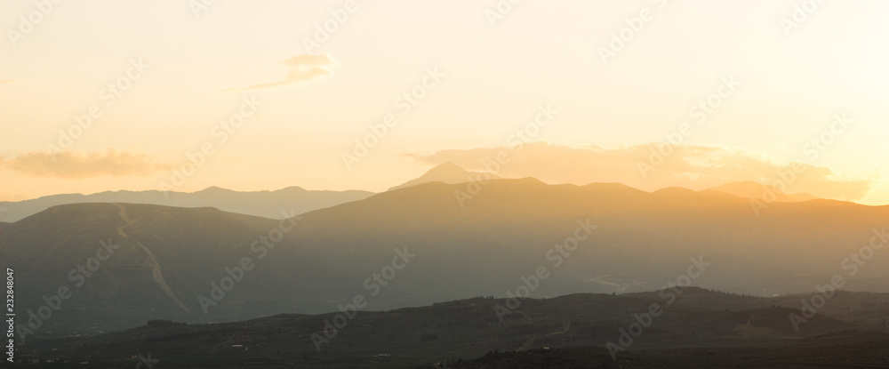Dramatic mountain silhouettes landscape scenery nature view in sun set evening time with sky of bright orange color 