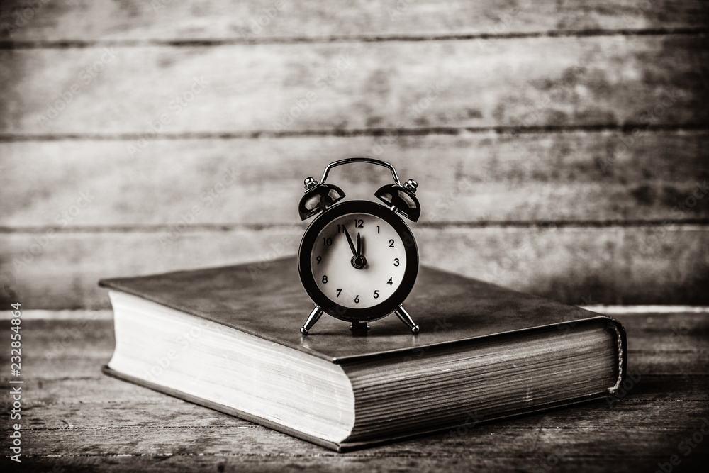 Alarm clock and book. Photo in black and white image style. Alarm clock and book. Photo in black and white image style.