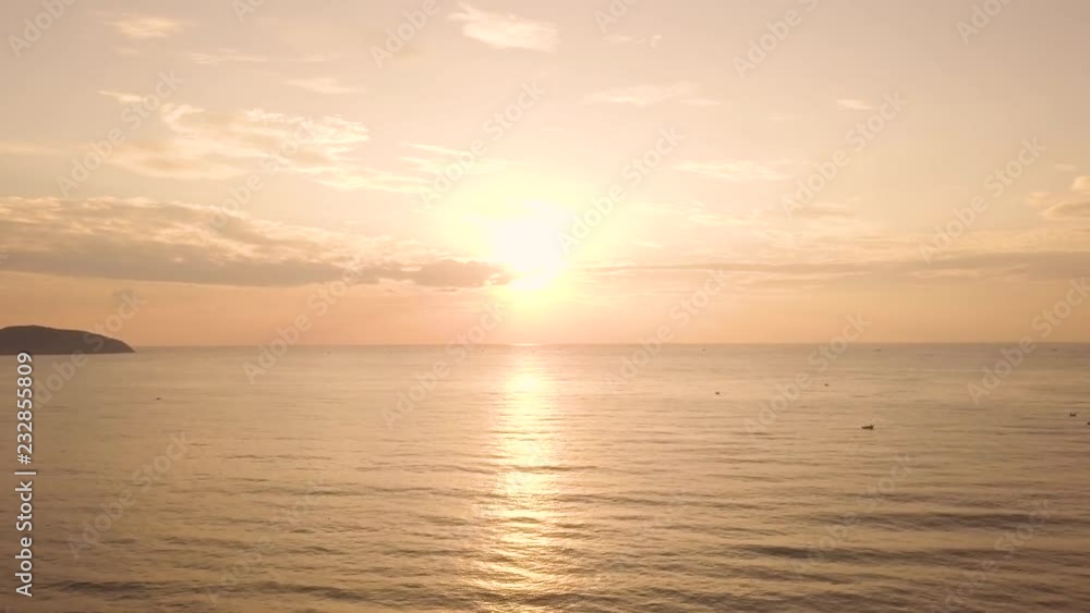 Aerial view colorful sunrise in sky over sea water on summer beach. Beautiful sunset in golden sky and sunshine reflection on sea water surface. View from flying drone early sunrise. Aerial view colorful sunrise in sky over sea water on summer beach. Beautiful sunset in golden sky and sunshine reflection on sea water surface. View from flying drone early sunrise.