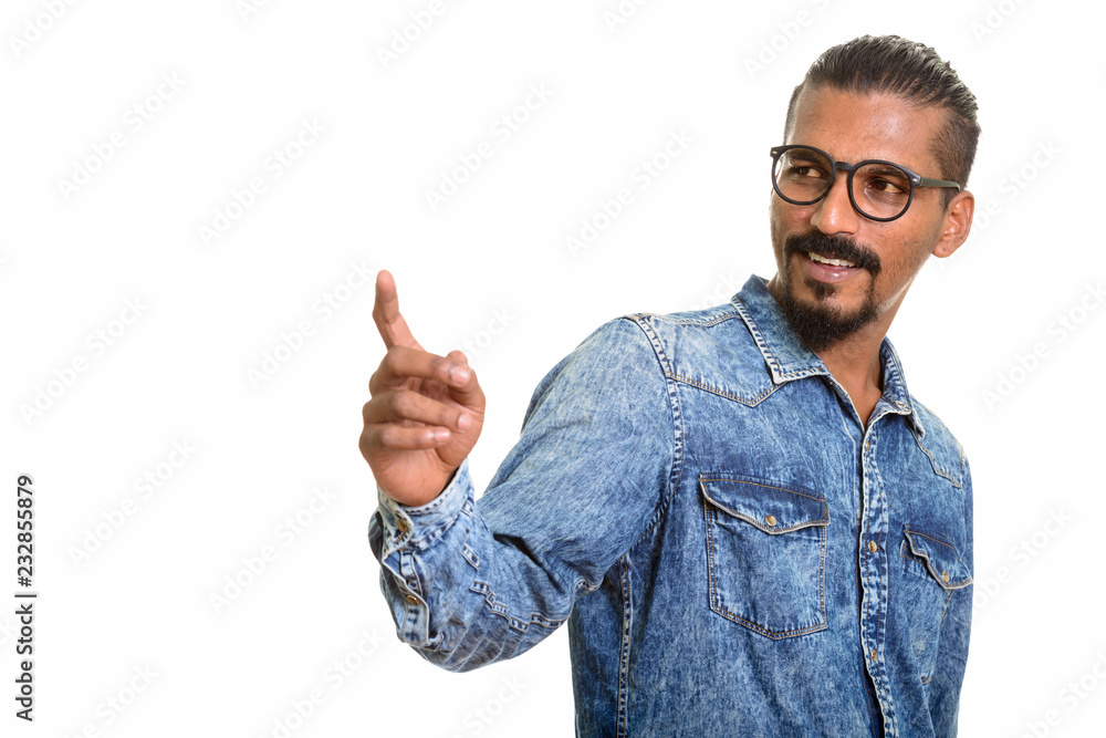 Young happy Indian man looking back and pointing finger Young happy Indian man looking back and pointing finger