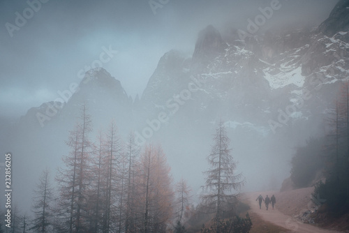 Three tourist walking in misty autumn nature in mountains