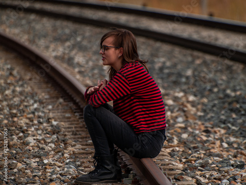 A lonely teen girl sitting on the train tracks